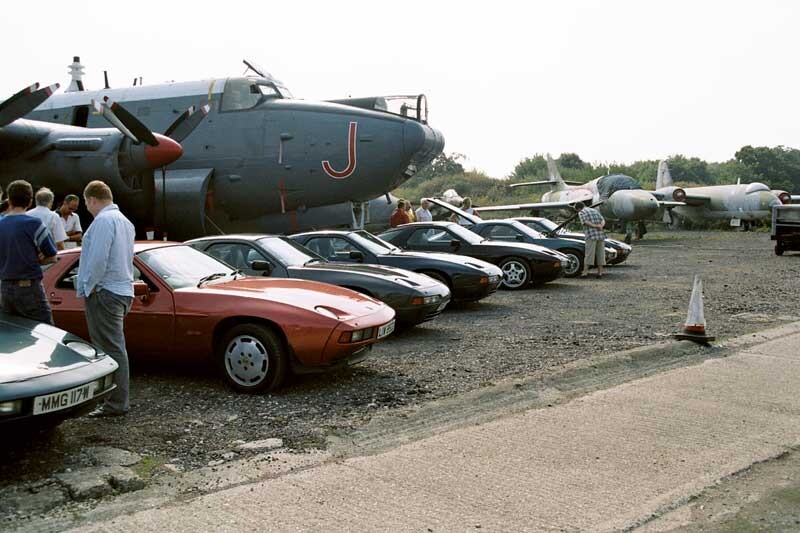 Porsche 928s parked by in front of an Avro Shackleton