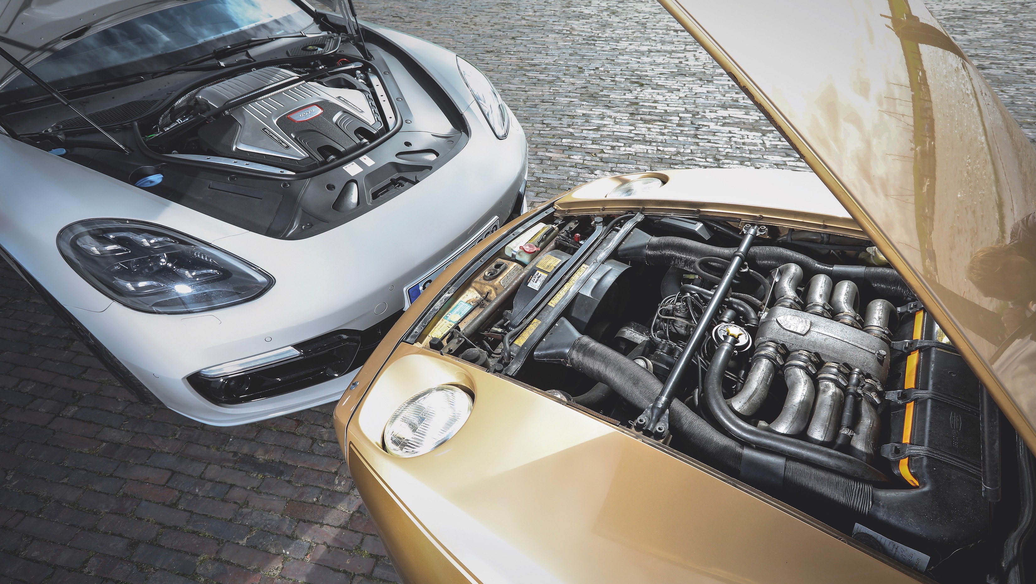 Bonnets open displaying the V8 engines of the Porsche 928 and Porsche Panamera Turbo